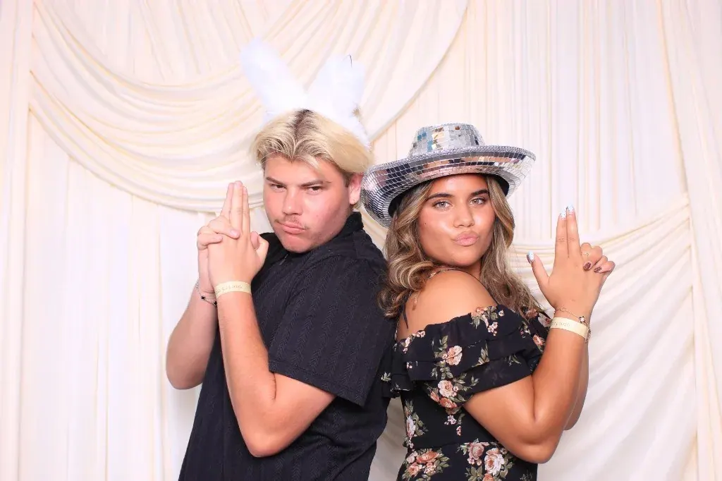Guests posing back to back with bunny ears and a disco cowboy hat