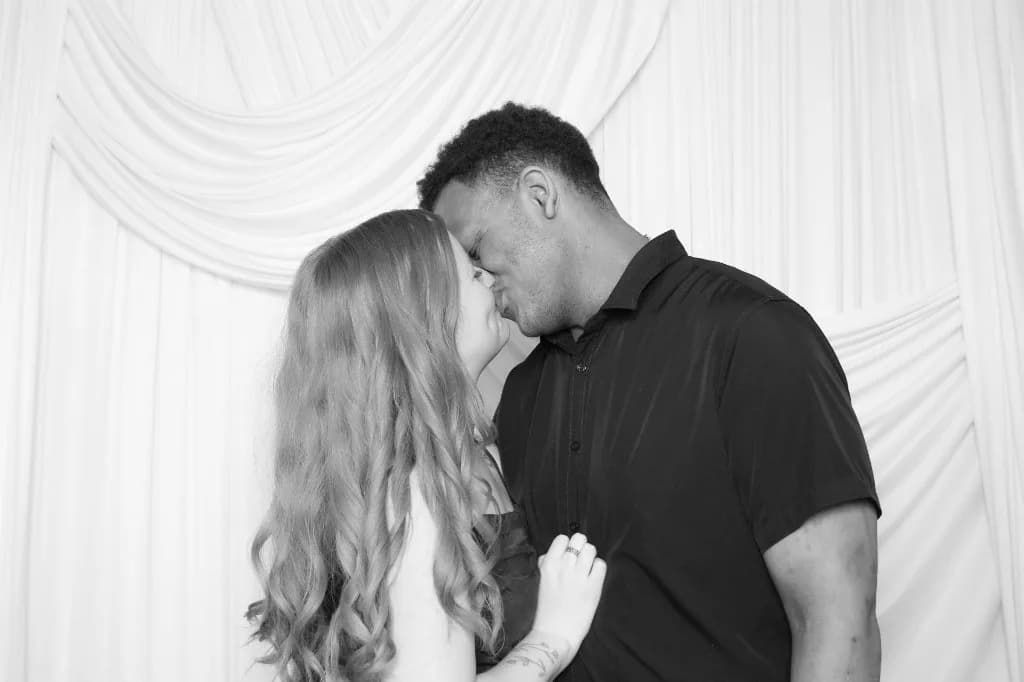 Couple sharing a kiss in black and white at the Proof Of Party booth
