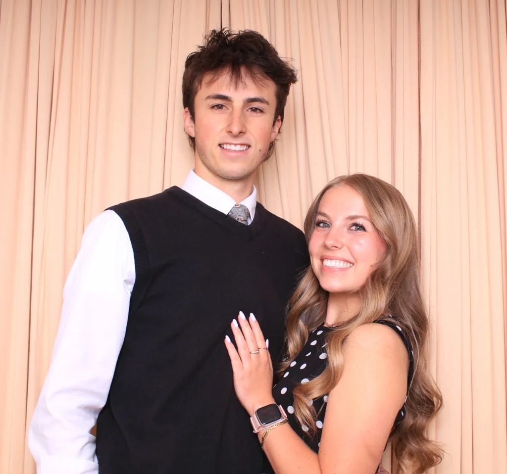 Young couple smiling against a peach pleated backdrop at the photo booth