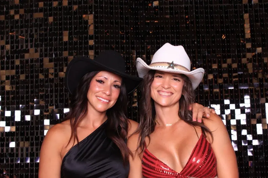 Two guests in cowboy hats against a gold shimmer wall