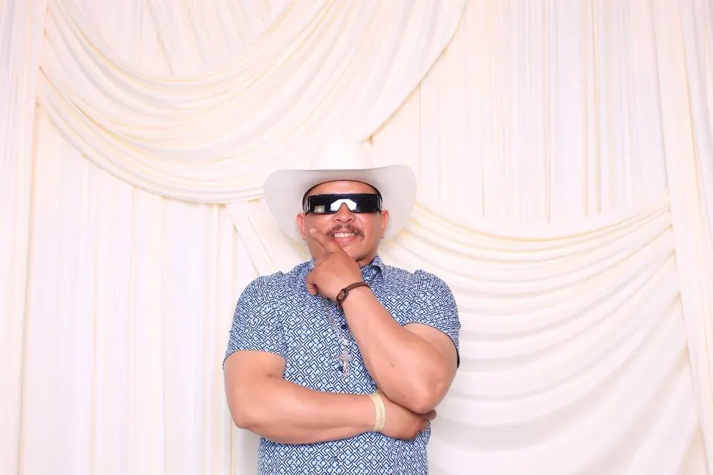 Guest posing in a white cowboy hat and sunglasses at the photo booth