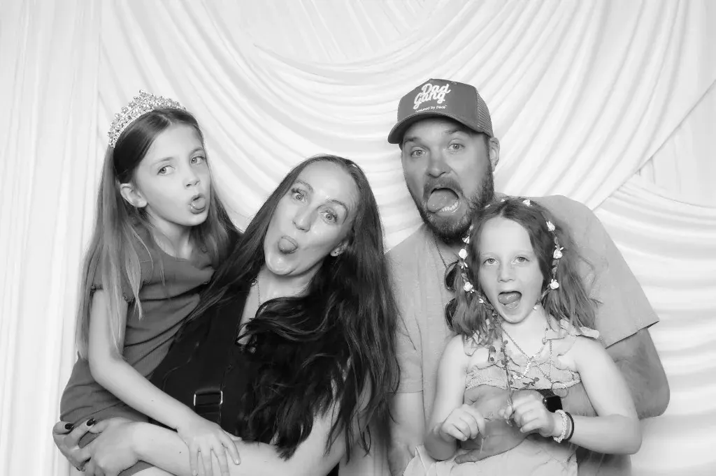Family of four making silly faces in a black and white booth photo