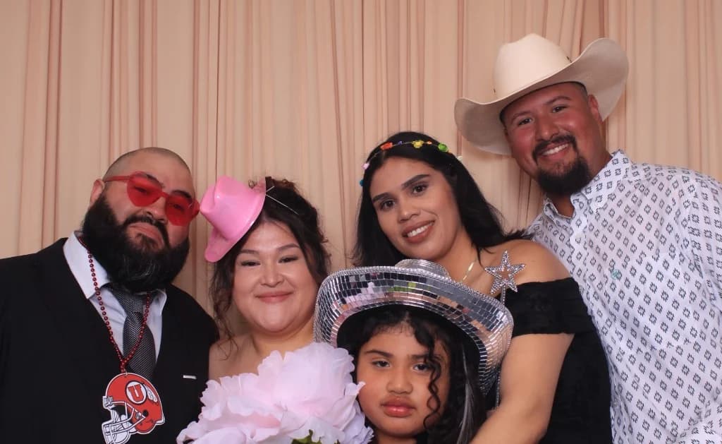 Quinceañera celebration guests posing with props against a peach luxury backdrop